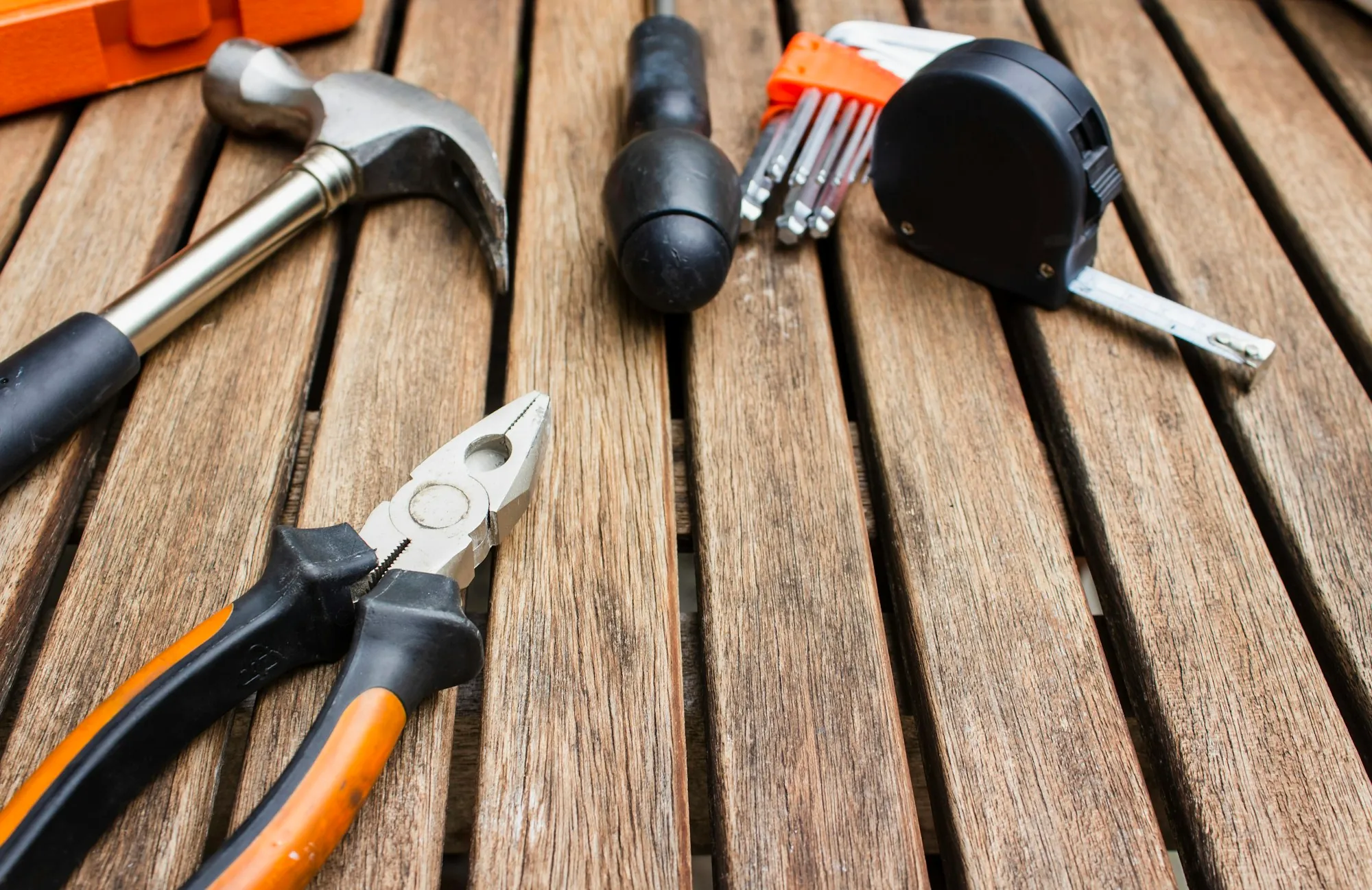 Pliers, hammer and tape measure on wooden boards